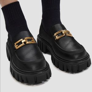 Platform black loafers with gold chain.